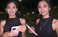 Camila Cooper en la calle de noche con top negro y collar sonriendo a cámara mientras sostiene un teléfono rosa